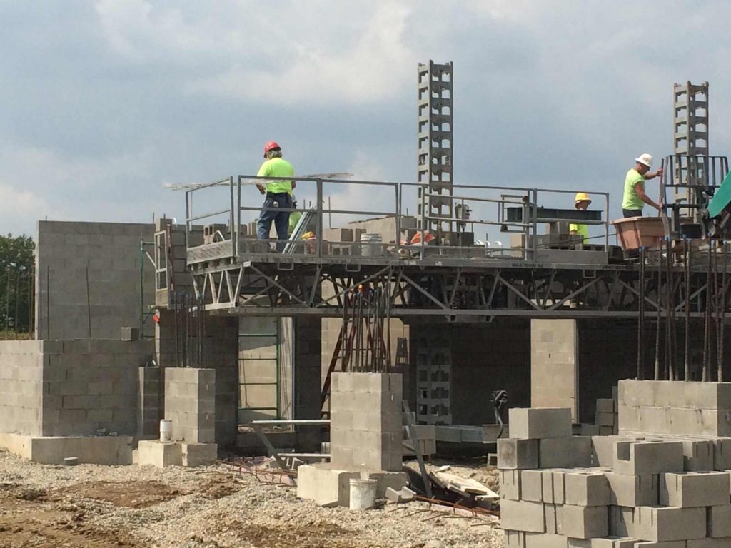 Construction workers on a scaffolding, building a wall with autoclaved aerated concrete